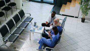 Doctor explaining medical expertise to elderly man during checkup visit consultation, nurse writing medication treatment on clipboard. Senior patient wearing cervical collar after neck injury photo