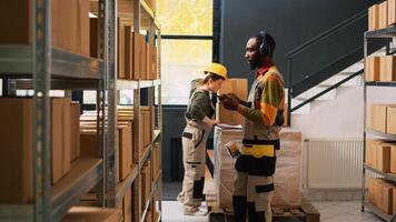 Young man having fun doing inventory, examining products on racks while he listens to music in storage room. Male depot employee dancing and looking at cargo, production stock. photo