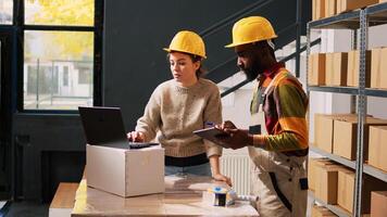 Two workers examining products stock in storage room, reviewing merchandise list on computer before shipment. Young team of people working on supply chain management, quality control. photo