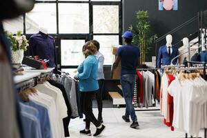 African american courier holding customers orders, leaving shopping centre. Man wearing delivery uniform, preparing to ship clients packages in modern boutique. Fashion concept photo