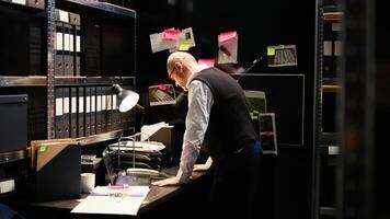 Stressed investigator on police duty, working with classified documents to solve case. Experienced law enforcement agent examining clues on board, reading witness statements files. photo