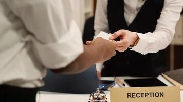 Close up of receptionist handing card key to elegant african american tourist during check in process. Business travelling guest ready to enjoy hotel stay after receiving room access photo