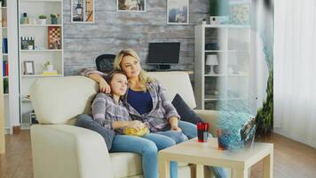 Happy family looking at nature documentary on AR projector display. Mother and daughter relaxing at home on couch, hugging and watching internet content on streaming services photo