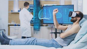 Man laying in hospital bed wearing high tech VR headset while scientist monitors his brainwaves on screen, using advanced equipment to enhance neurology research understanding of human mind photo