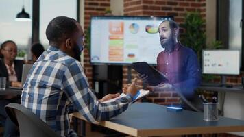 Businessman watching augmented reality training video visualization of team leader explaining how to solve tasks at high tech office desk computer. African american executive with hologram supervisor photo