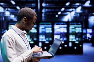 Programmer typing cloud computing service business disaster contingency plan on laptop to provide quick restoration of service, limiting downtime and minimizing interruptions to server hub operations photo