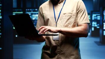 Close up of technician walking between operational server clusters in high performance computing data center, ensuring optimal operations. Admin monitoring energy consumption across systems photo