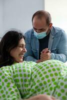 futuro padre en pie junto a mujer durante niño nacimiento en hospital pabellón, embarazada esposa gritando y emprendedor durante cesariano cirugía. paciente con el embarazo consiguiendo dentro labor en maternidad clínica foto