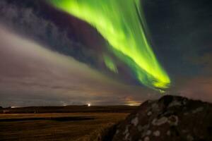 At sundown in Iceland, aurora borealis brightens up night sky in outstanding hues of green and violet, forming magical icelandic landscape. Stars sparkle around northern lights. photo