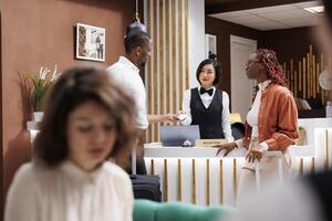 Guests receiving key card at front desk, doing check in process and preparing to register for hotel room access. Receptionist helping tourists with access control at front desk, welcome people. photo