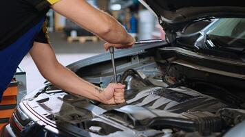 Certified mechanic in car service uses wrench to tighten bolts after fixing vehicle parts. Repair shop employee utilizing professional tools to make sure automobile is properly working, close up photo