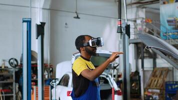 African american mechanic in car service using virtual reality goggles to visualize automobile components in order to fix them. Repairman wearing futuristic vr headset to test vehicle engine photo