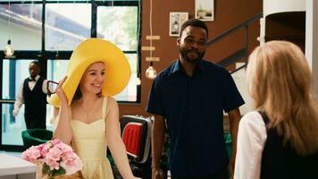 Hotel employee greeting guests at reception, welcoming happy people on honeymoon trip. Woman front desk worker talking to travellers about seaside tropical leisure activities at resort. photo