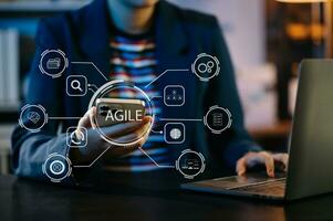 ágil desarrollo metodología concepto. negocio mano utilizando ordenador portátil computadora y tableta con virtual pantalla ágil icono en moderno oficina digital tecnología concepto. foto