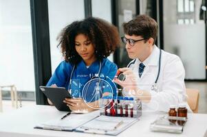 Doctor Talks With Professional Head Nurse or Surgeon, They Use Digital tablet Computer. Diverse Team of Health Care Specialists Discussing Test Result on desk photo