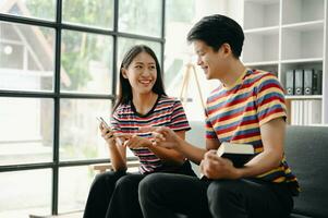 Two asian students learning together online with a laptop, tablet and tutor together in living room photo