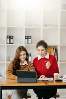 Businesswoman leading team meeting and using tablet and laptop computer with financial in coworking office photo