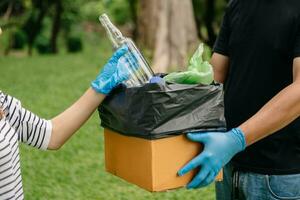 personas mano participación basura botella el plastico y vaso poniendo dentro reciclar bolsa. el plastico concepto. foto