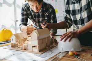 Close up shot of scale model house on table with architects. Two architects making architectural model in office together. to form a new building photo