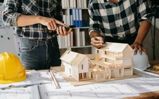 Close up shot of scale model house on table with architects. Two architects making architectural model in office together. to form a new building photo