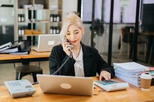 Happy asian business woman have the joy of talking on the smartphone, tablet and laptopon the modern office photo