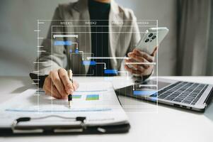 gerente de proyecto trabajando y actualizando tareas con hitos de planificación de progreso y diagrama de programación de diagramas de gantt. negocios que trabajan con teléfonos inteligentes, tabletas y computadoras portátiles foto