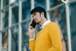 Asian businessman looks at smart phone reads news from phone and writes in messenger outside office photo