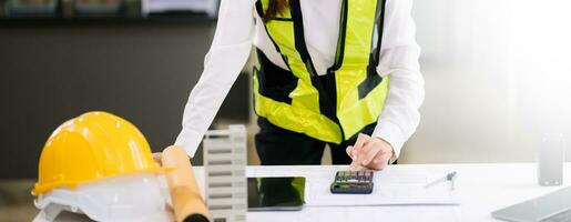 business man hand working and laptop with on on architectural project at construction site at desk in office photo