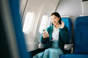 Young Asian executive excels in first class, multitasking with digital tablet, laptop and smartphone. Travel in style, work with grace. photo