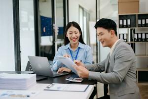 Two business workers talking on the smartphone, calculator and using laptop at the modern office. photo