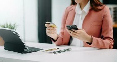 Woman using smart phone for mobile payments online shopping, omni channel, sitting on table, virtual icons graphics interface screen photo