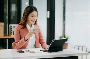 Asian Woman using smart phone for mobile payments online shopping,omni channel,sitting on table,virtual icons graphics interface screen photo