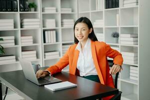 Beautiful Asian business woman typing laptop and tablet Placed at the table at the modern office photo