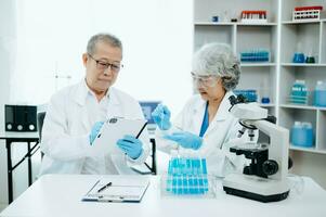 Two scientist or medical technician working, having a medical discuss meeting with Asian senior female scientist supervisor in the laboratory with online reading, test samples and innovation photo