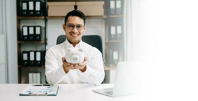 Asian Man are putting coins in a piggy bank for a business that grows for profit and saving money for the future. planning for retirement concept photo