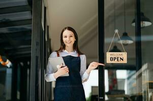 Startup successful small business owner sme woman stand with tablet and chart in cafe restaurant. woman barista cafe owner. photo