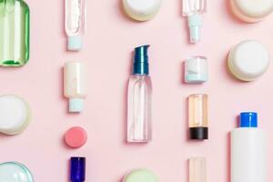 grupo de botellas de plástico para el cuidado del cuerpo composición plana con productos cosméticos sobre fondo rosa espacio vacío para su diseño. conjunto de envases cosméticos blancos, vista superior con espacio de copia foto