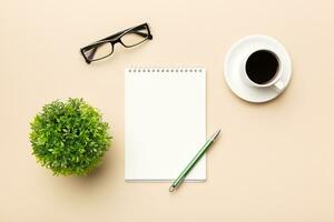 Modern office desk table with notebook and other supplies with cup of coffee. Blank notebook page for you design. Top view, flat lay photo