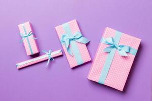 Gift box with blue bow for Christmas or New Year day on purple background, top view photo