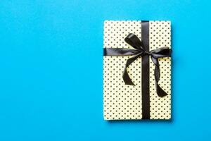 envuelto Navidad o otro fiesta hecho a mano presente en papel con negro cinta en azul antecedentes. presente caja, decoración de regalo en de colores mesa, parte superior ver con Copiar espacio foto