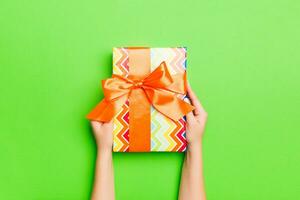 Top view of female hands holding christmas or other holiday handmade present box package in the palms, flat lay table background with copy space photo