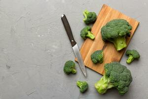 fresh green broccoli on wooden cutting board with knife. Broccoli cabbage leaves. light background. Flat lay photo