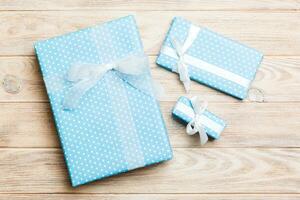 paper gift box with colored ribbon on orange wood background. top view with copy space Christmas holiday concept photo