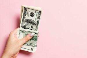 Top view of female hand holding a pack of one hundred dollar bills on colorful background. Wage and salary concept with empty space for your design photo