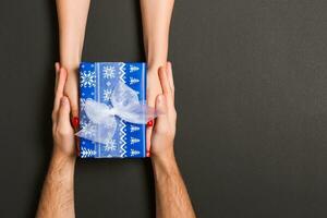 Top view of couple giving and receiving a gift on colorful background. Close up of romantic concept photo