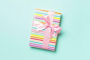 Gift box with pink bow for Christmas or New Year day on blue background, top view with copy space photo