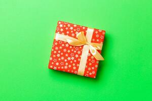 Gift box with gold bow for Christmas or New Year day on green background, top view with copy space photo