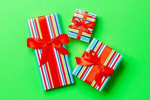 envuelto Navidad o otro fiesta hecho a mano presente en papel con rojo cinta en verde antecedentes. presente caja, decoración de regalo en de colores mesa, parte superior ver foto