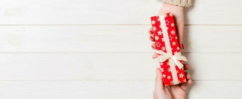 Top view of a man and a woman holding a gift on wooden background. Concept of giving and receiving a present with copy space photo