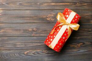 Beautiful gift box with a gold bow on the dark wooden table. Top view banner with copy space for you design photo